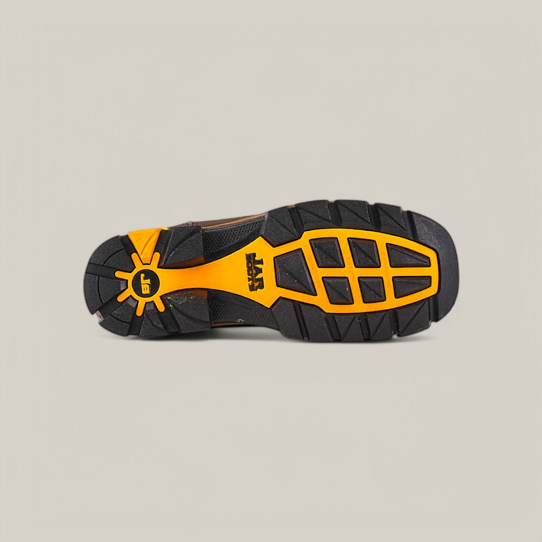 The image features the rugged tread pattern of the Amazonas Dark Brown Composite Toe - E6256. The predominantly black, waterproof sole has orange accents and a sun-like design near the heel, with SRX prominently displayed at its center, highlighting durability.