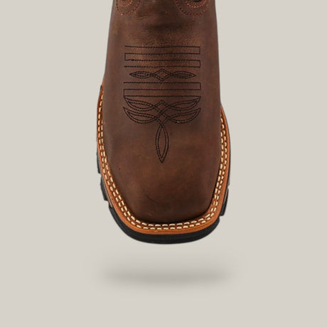 Close-up of the Amazonas Tanger Soft Toe - E6257, highlighting intricate stitching on its square toe. The boot features a durable light brown stitched sole against a plain gray background.