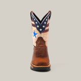 The Aventajado Penac Soft Toe - E6282 features a front view showcasing a brown leather foot and a beige shaft with a star-spangled blue, red, and white design reminiscent of the American flag. Its slightly pointed toe pairs with a durable black sole for an ideal blend of style and resilience.