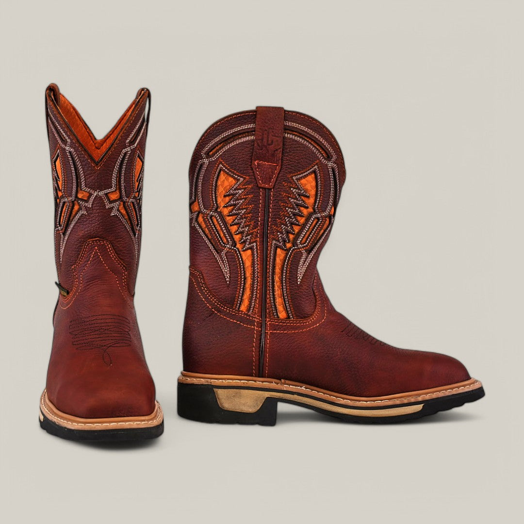 The Floter Shedron Composite Toe - E6987 boots are durable brown cowboy boots with intricate orange stitching on the shaft, featuring rounded toes, a tan leather sole, and black rubber heels; one boot stands upright while the other faces forward.