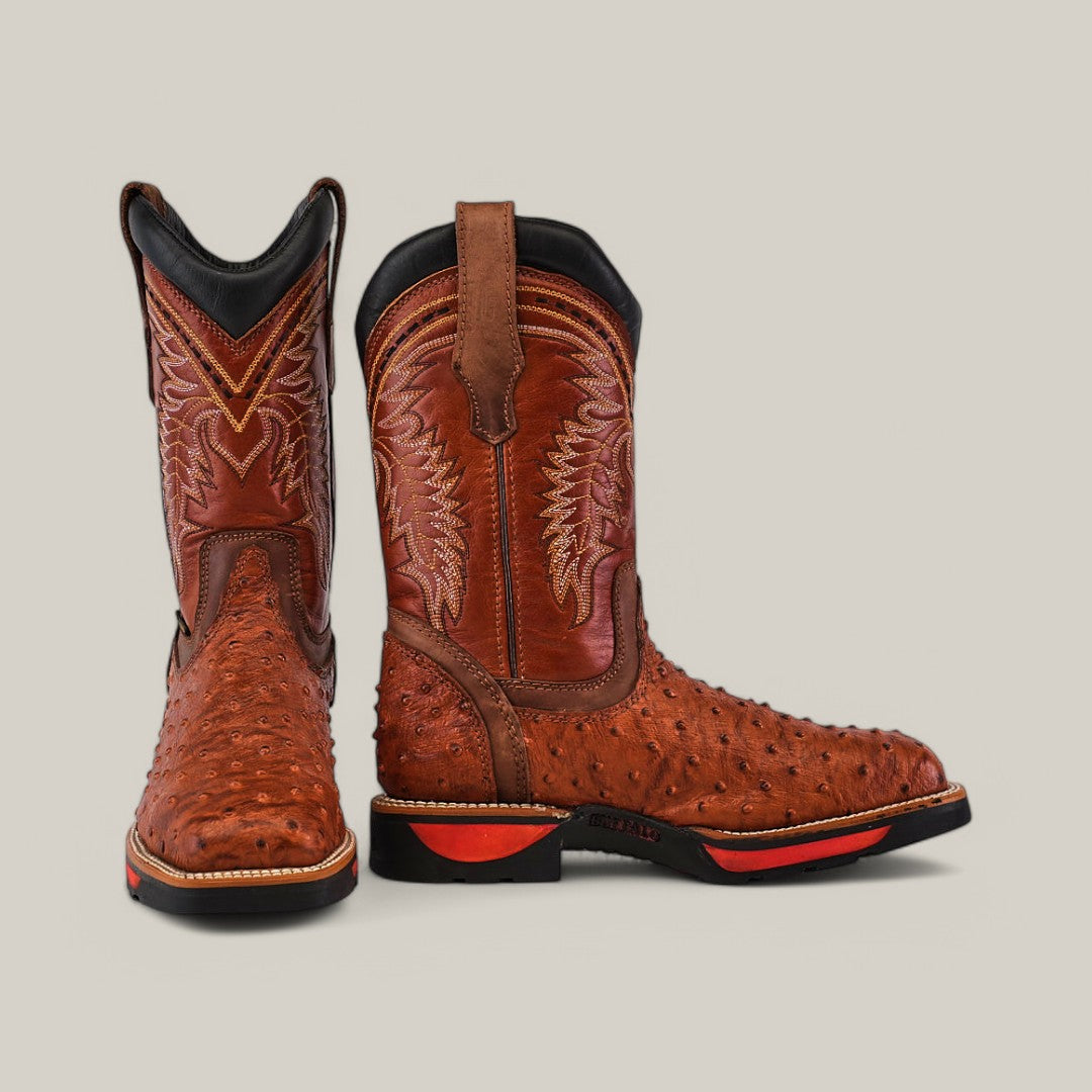 The Ostrich Print Cogñac Composite Toe - E6022 showcases Texas Country Work Boots style with intricate stitching and ostrich leather texture. Featuring a black collar and red sole accents, these resilient brown cowboy boots stand out against a plain background, promising both durability and style.