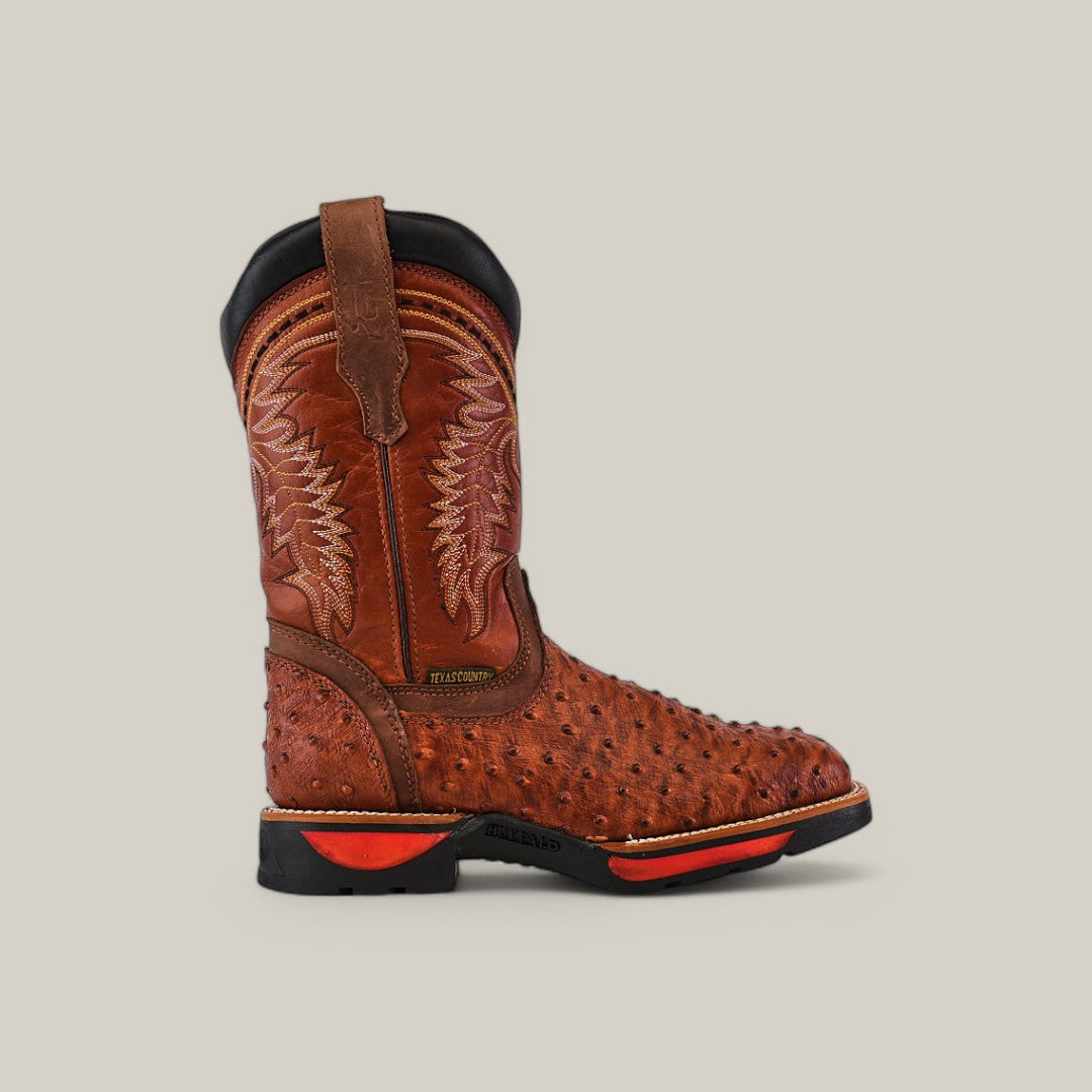 The Ostrich Print Cogñac Composite Toe - E6022 by Texas Country Work Boots boasts a single brown cowboy boot with intricate shaft embroidery, textured ostrich leather finish, and a rubber sole with red accents, all shown against a plain beige background.