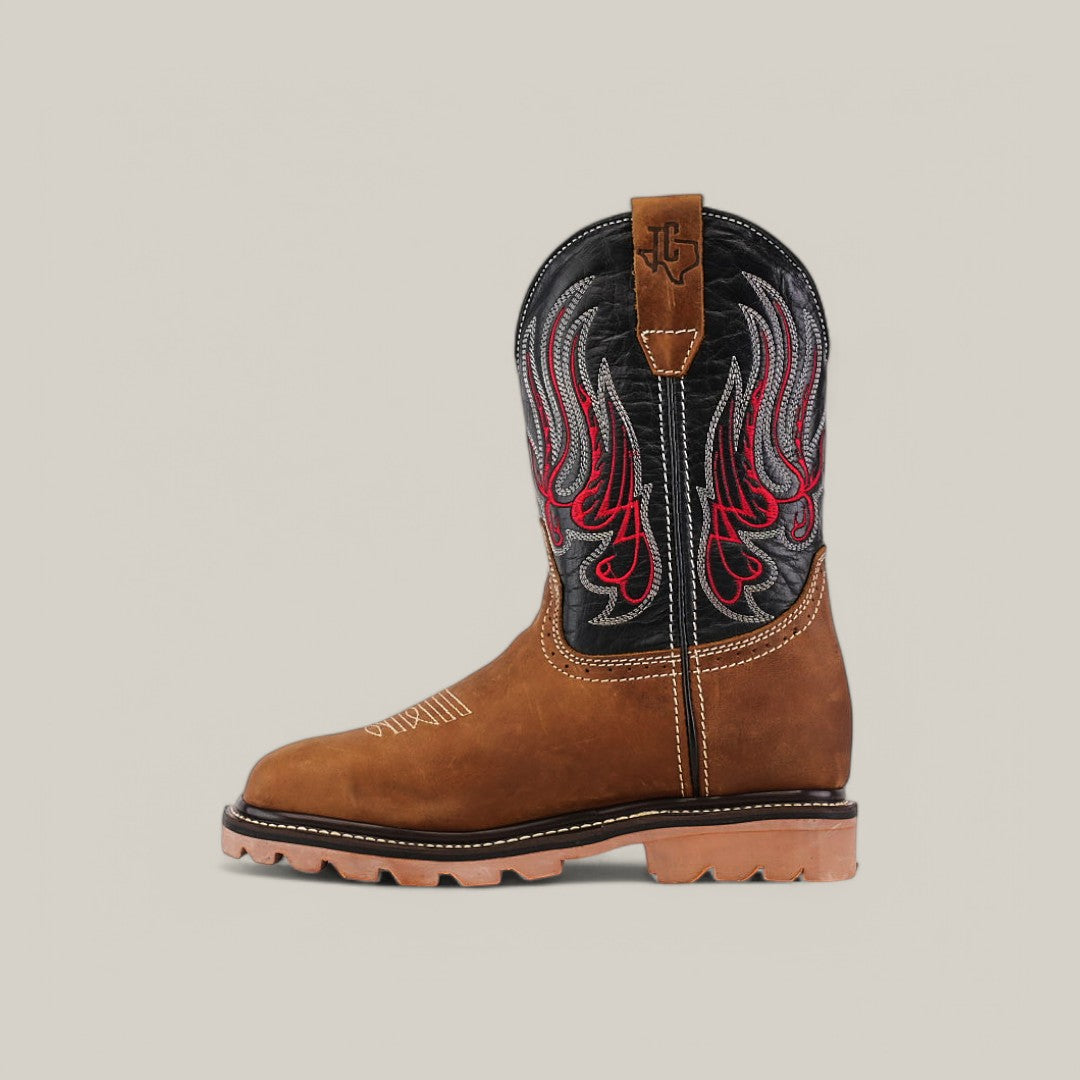 The Crazy Tang Soft Toe - E6015 features a black shaft with red and gray flame embroidery, brown cowboy boot styling, stitched details, and a rugged tan treaded rubber sole. Perfect for Texas Country Work Boots, it includes a pull tab at the top.