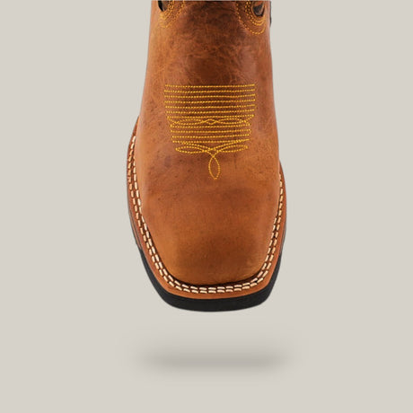 The Alazan Sand Soft Toe - E6081 features a square toe design with intricate yellow stitching on the toe and white detailing along the sole. Built for durable comfort, this Texas Country Work Boot stands out against a plain grey background.