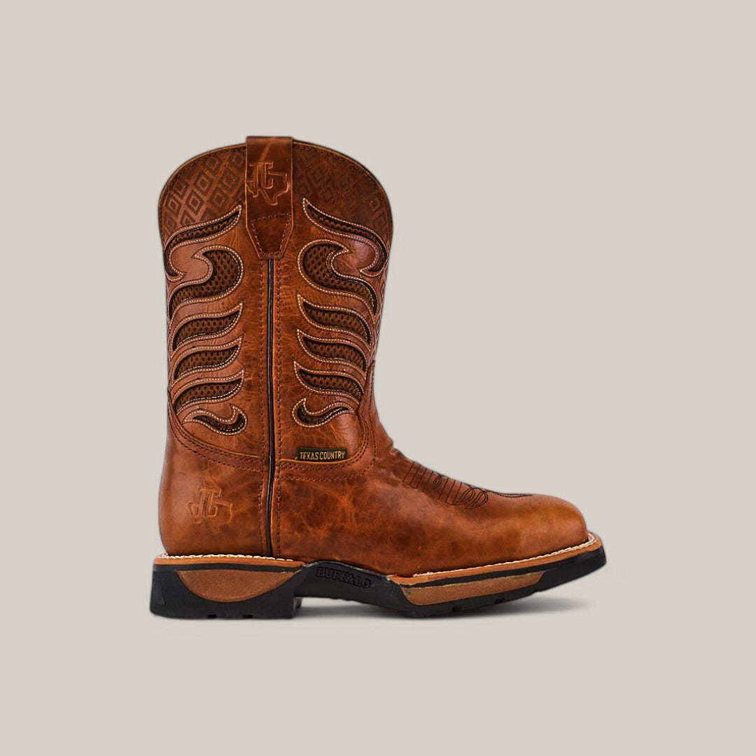 The Crater Honey Soft Toe - E6087 by Texas Country Work Boots is a brown leather cowboy boot with decorative stitching on the shaft, textured patterns, a black sole, and a pull tab at the top. It embodies rugged style and is set against a plain beige background.