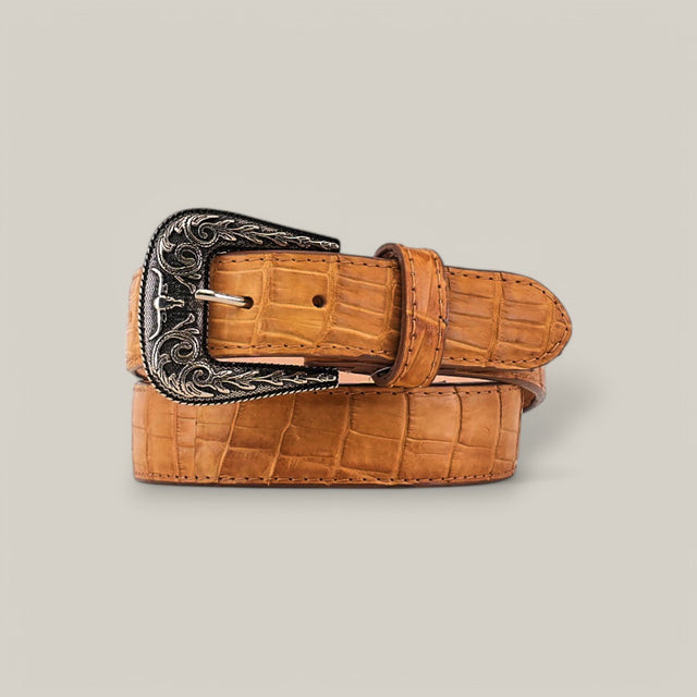 This Exotic Full Quilt Alligator belt in fawn features a textured surface with an ornate Texas buckle, adorned with intricate floral designs against a beige background.