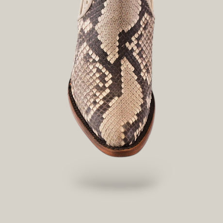 The image features the toe area of the Plunge Natural Python Zipper & Cut Out - Round Toe - CU570 boot in brown and cream snake-print leather. The python design adds texture and style, set against a solid background that highlights the craftsmanship of this unique footwear piece.