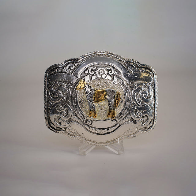 The Floral Full Horse Buckle is a decorative Texas-style buckle made from alpaca silver. It showcases an engraved gold horse at the center, surrounded by ornate western designs and floral motifs, making it a standout accessory.