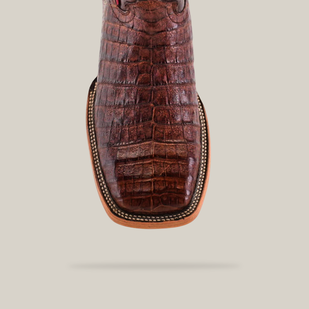 The Exotic Caiman Belly - Brown - Square Toe boot features intricate stitching, a light tan trim, and is made of genuine caiman leather. Positioned vertically on a plain light gray background, it casts a soft shadow.