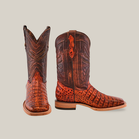 The Exotic Caiman Belly - Brandy - Square Toe boots, beautifully designed in brown with intricate patterns and textures, are crafted from authentic caiman leather. On a plain background, one boot stands upright while the other is slightly tilted to display its side view.