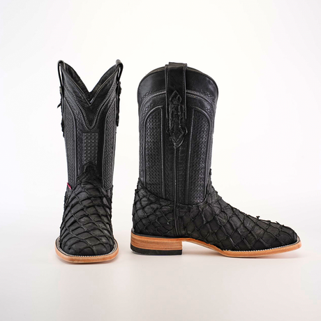 A pair of Exotic Piraruco Fish Matte Black square toe cowboy boots with textured reptile pattern and wooden soles stand upright on a white background, showcasing their authentic leather, detailed stitching, and pull straps.