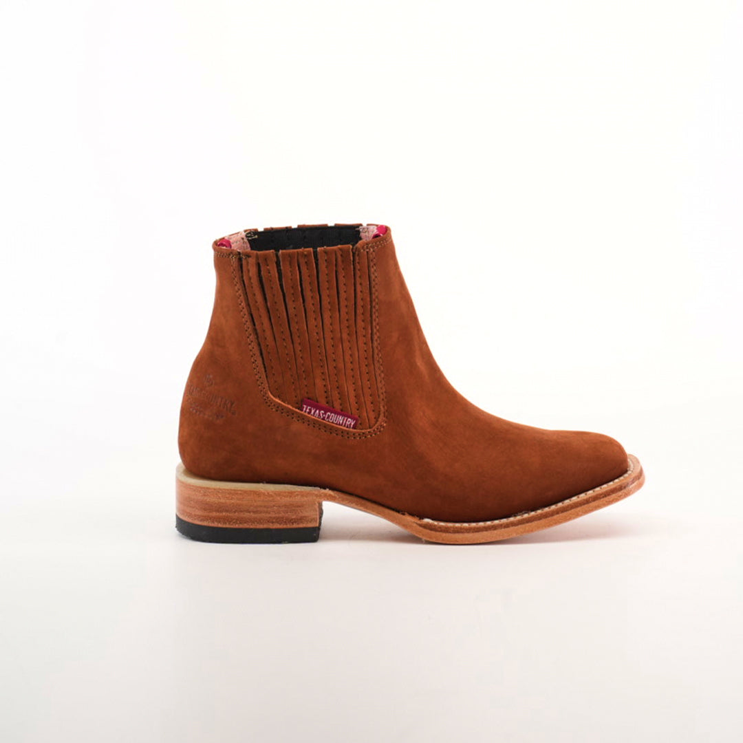 The handcrafted brown suede ankle boot with elastic side panels and a small heel resembles the Prime Suede Brick Square Toe, beautifully highlighted against a plain white background.