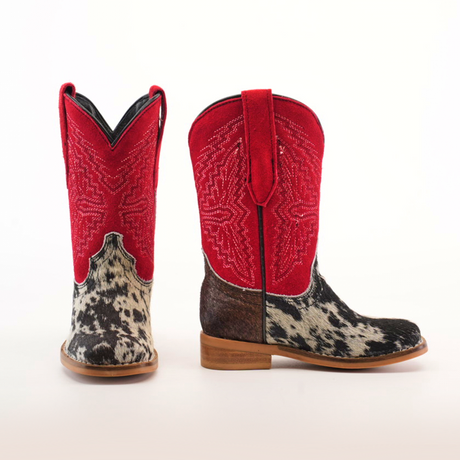 The Cowhide Hair Pinto Square Toe boots showcase red uppers with intricate stitching, complemented by black and white speckled cowhide lower sections. Their western style comes complete with brown soles, all set against a plain white background.