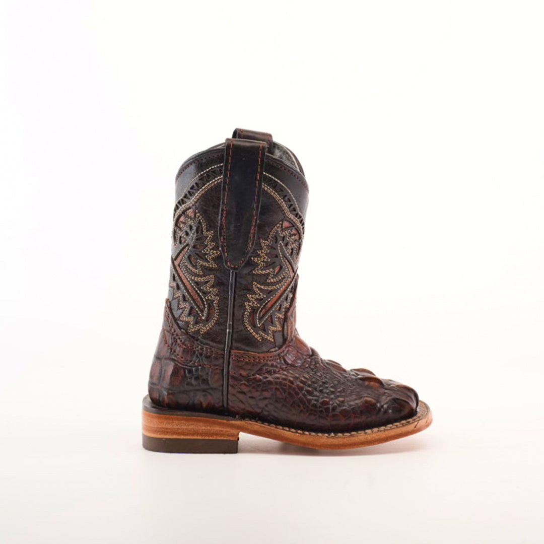 The Alligator Head Print Rustic Honey Square Toe cowboy boot, made from premium leather, features intricate stitching and a textured brown design. With a sturdy sole and top loop for easy pull-on, this upright boot against a plain white background embodies the essence of western fashion.