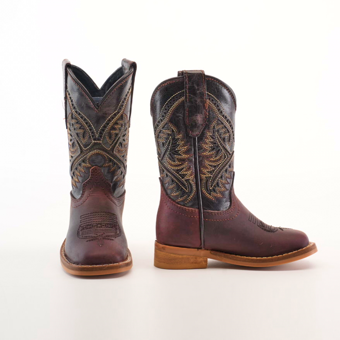 The Salvage Almond Square Toe boots are crafted from premium cowhide leather with intricate shaft patterns. They feature a dark brown color with contrasting light brown soles and stitching, all showcased against a plain white background.