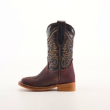 The Salvage Almond Square Toe boot, made from premium cowhide leather, showcases intricate stitching and a rich brown color. It features a low wooden heel, a pull tab at the top, and an elegant square-toe design against a plain white background.