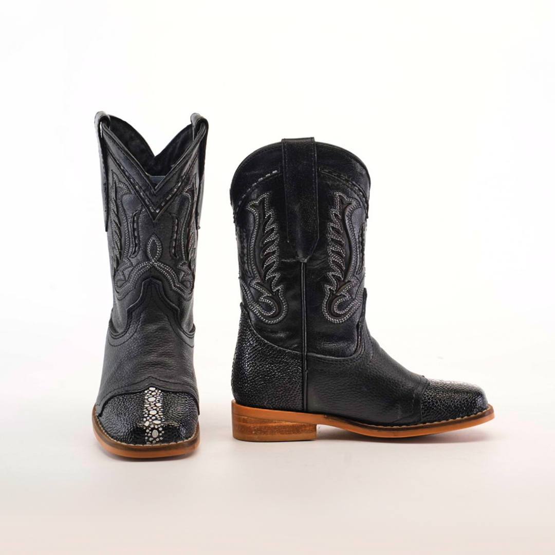 The Stingray Half Cowhide Print Black Rodeo Toe boots exude western charm with intricate stitching and snake-like textured accents. Crafted from cowhide leather, they feature a high shaft and wooden soles, all set against a plain white background.