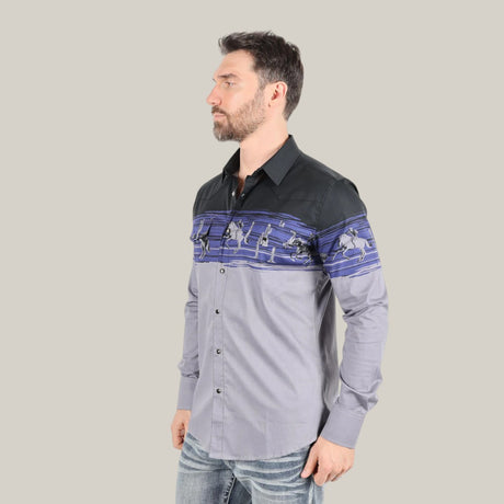 Wearing a Modern Fit Cotton Stretch Rodeo Panoramic Print Shirt (AZL9941), featuring blue and black figure designs, a man with short dark hair and a beard pairs it with blue jeans. He poses against a plain backdrop facing left.