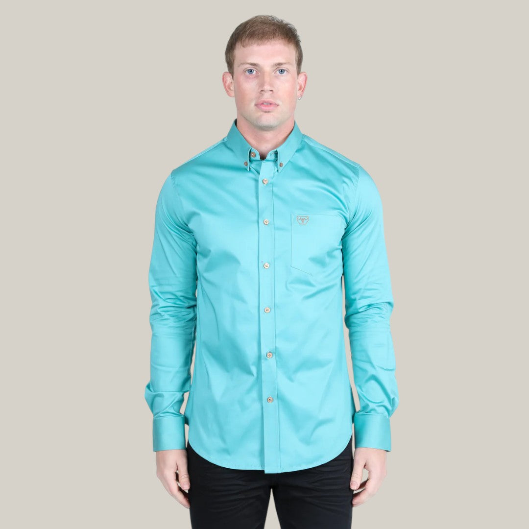 A person wearing a Men’s Single Pocket Logo Modern Fit Stretch Dress Shirt in turquoise (CTL9829) stands against a light grey background. They have short hair, look directly at the camera, and have their arms at their sides.