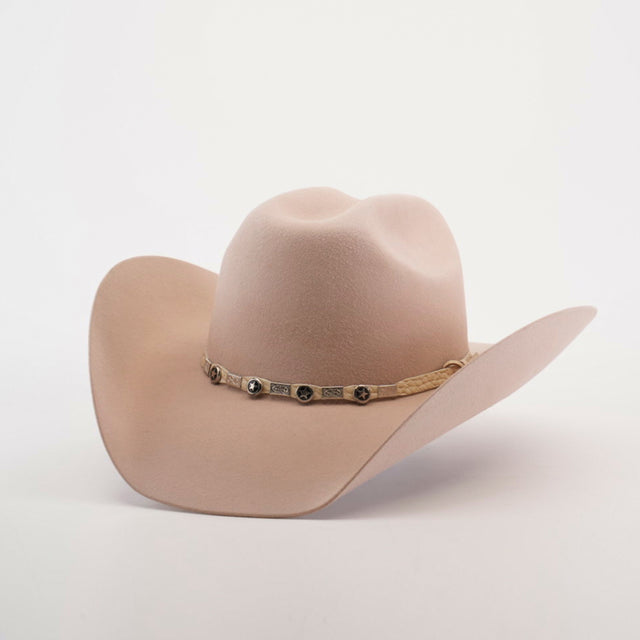 The 6X Bull Belly, a beige western hat with a wide brim and a decorative band with metallic embellishments, stands against a plain white background, epitomizing luxury western wear.