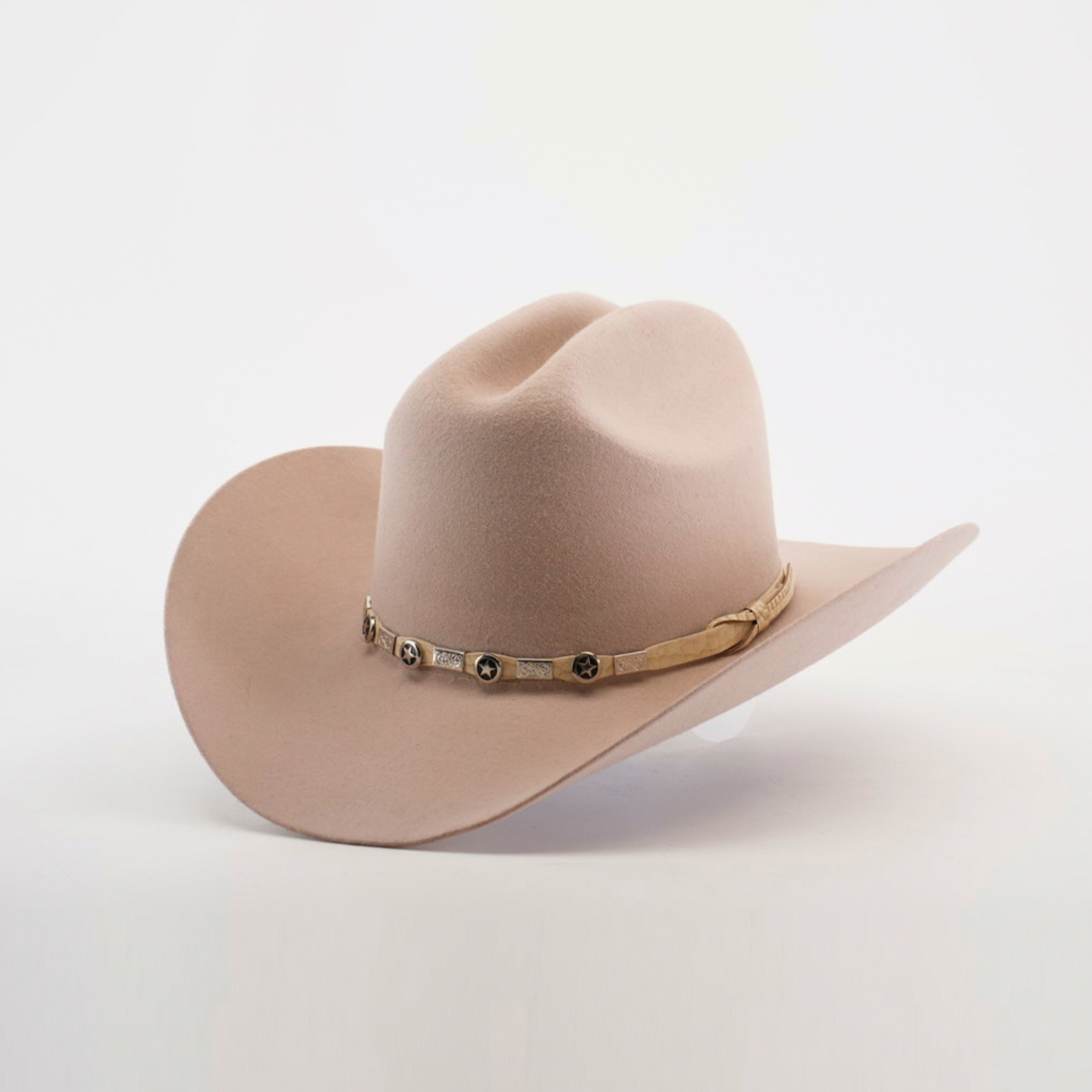 The 6X Sinaloa Belly, a light beige cowboy hat crafted from sheeps wool, showcases a wide brim and a decorative band with metallic accents. Positioned against a white background, it captures the spirit of Western heritage.