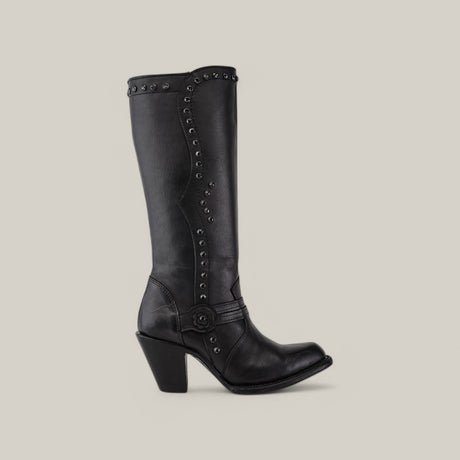 The Denali Crystals Tall Shaft Black - Round Toe boot from the Platinum Collection features decorative metal studs and a strap with a circular buckle. This black knee-high boot has a smooth finish and is set against a plain beige background.