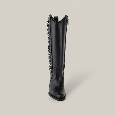 This Francia Rings Tall Shaft Black boot from the Platinum Collection, with a pointed toe and silver chain detailing on a black leather body, sits elegantly against a plain, light grey background. It merges classic style with modern elegance effortlessly.