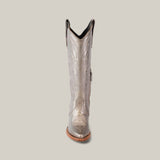 The Linda Tall Shaft Mercury - J Toe boot from the Platinum Collection showcases a metallic silver design with intricate embroidery on the shaft, featuring a slightly pointed toe and stacked heel against a plain beige background for a striking look.