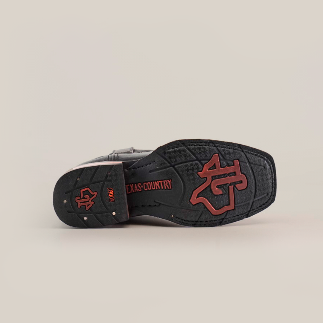 The image highlights the Barcelona Black Slip Resistant Sole of a black cowboy boot with red accents, featuring TEXAS COUNTRY and a large stylized logo. Crafted from premium leather, this boot is set against a plain white background.