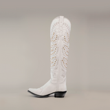 The Crystals Wings Frost White cowboy boot showcases a tall shaft with a snip toe, adorned with decorative perforations and gold studs. Its elegant design is completed by a leather sole and black heel.