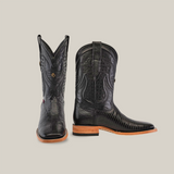 A pair of Exotic Lizard - Black boots boasts intricate stitching and a textured pattern, featuring a wooden sole and square toes. Positioned against a plain white background, it displays both the side and front profiles stylishly.