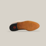 The image showcases the Prime Suede Pearl Round Toes sole with a smooth tan leather bottom and edge stitching. Inspired by cowboy style, it features a black heel with a red rubber insert for better grip.