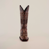 The Texas Cross Glitterbomb Brown boot is crafted by master bootmakers from premium leather, featuring intricate stitching with wings and a cross emblem. It has a mid shaft and narrow square toe, shown from the front against a plain white background.