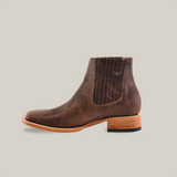 The Alamo Brown Square Toe boot highlights Western style with brown leather, stitched details, and a low stacked wooden heel. Handcrafted with black elastic side panels and a light sole featuring a small black rubber grip section.