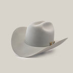 The 1000X Imperial Platinum is a light gray Larry Mahan cowboy hat with a wide brim, distinct crown crease, and decorative band with metal ornament, angled slightly on a plain backdrop, capturing the iconic western style.