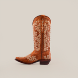 The Cleo Honey Crystals boot features intricate white floral embroidery on a brown background, embodying classic Western style with its handcrafted design, snip toe, and low heel.