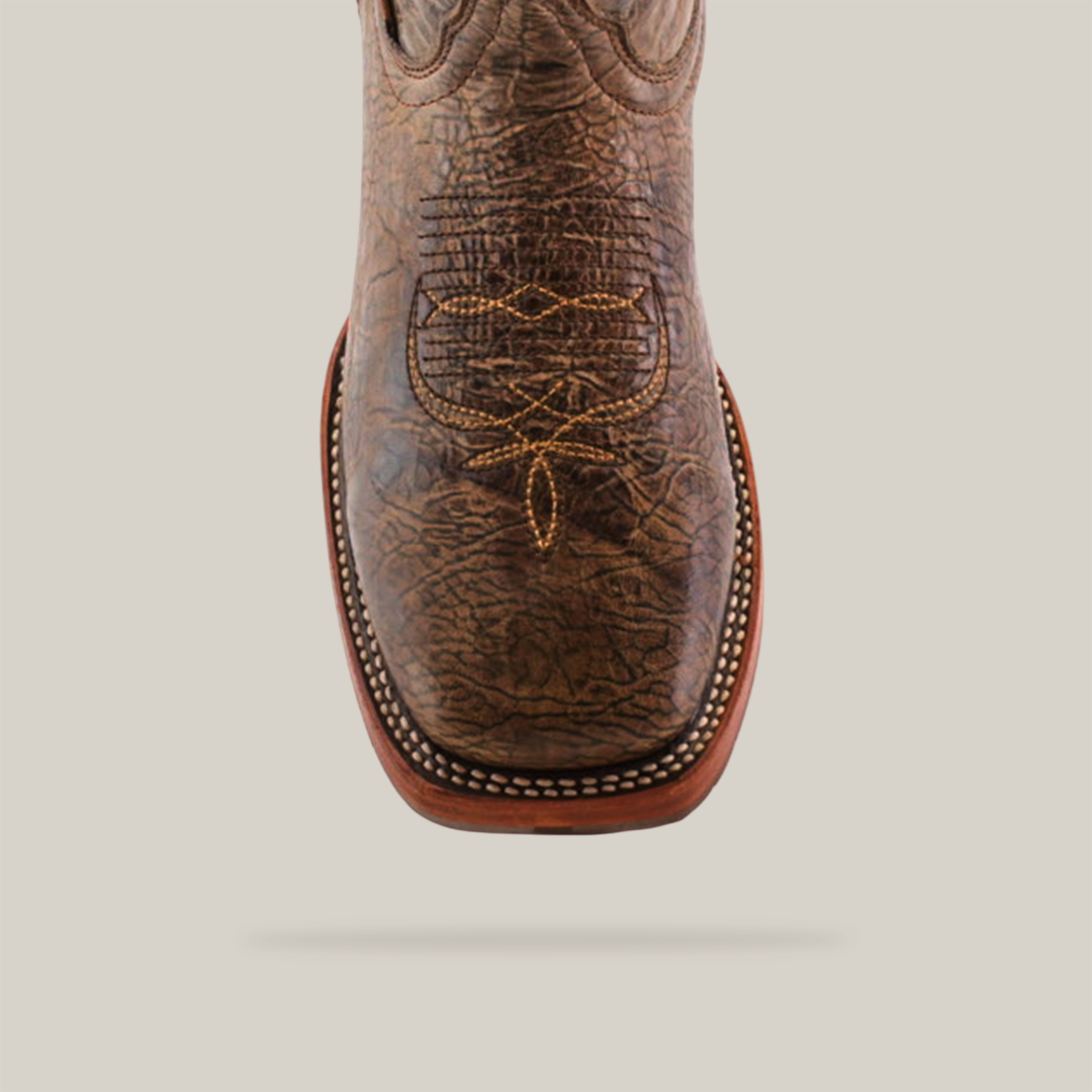 Close-up of the Rustic Camel Brown Boot made from premium cowhide leather, featuring intricate stitching, a square toe, and a decorative pattern against a white background. It includes a slip-resistant sole for added stability.