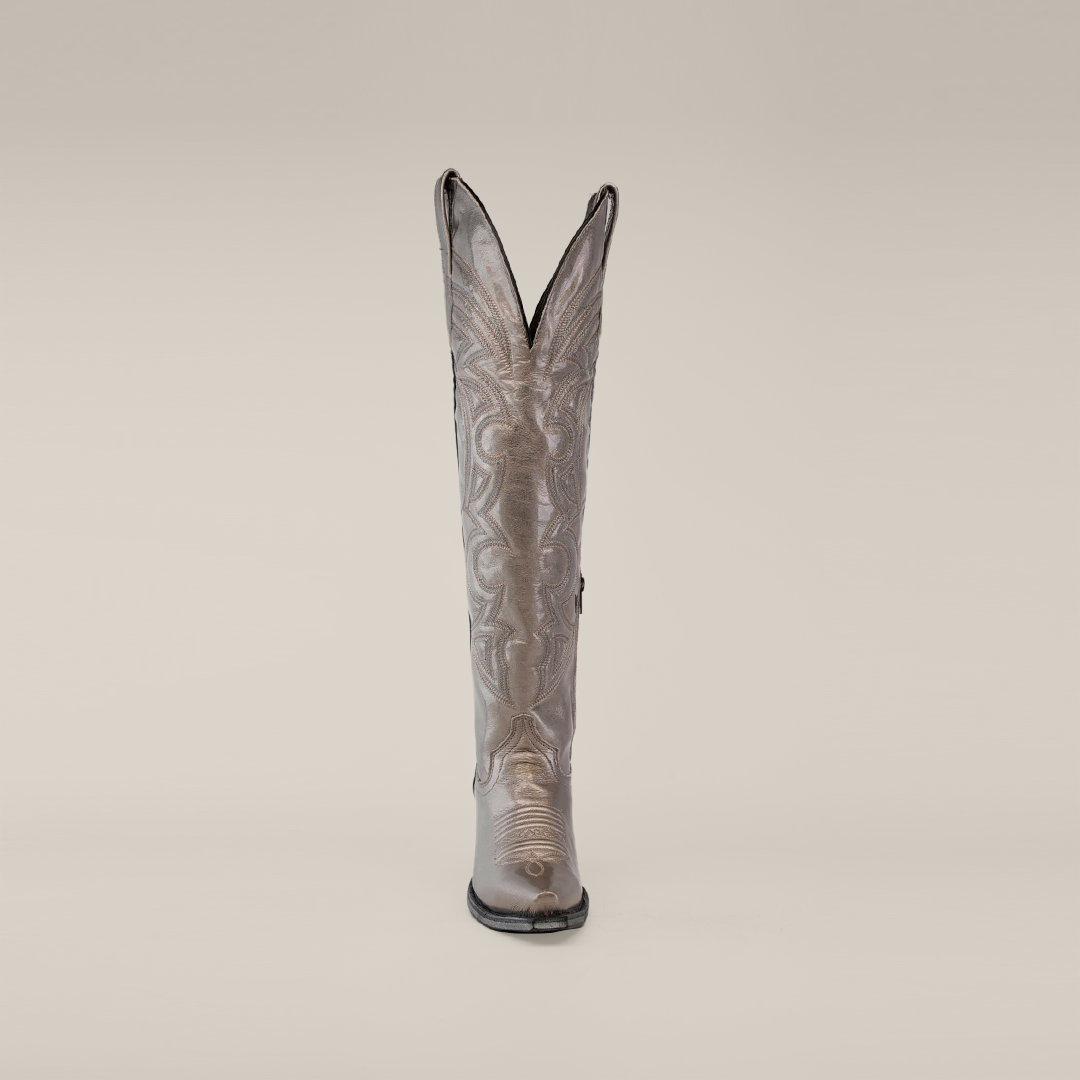 The Taylor Mercury cowboy boot features a tall silver shaft with intricate stitching, a snip toe, and a durable leather sole, all set against a plain white background.