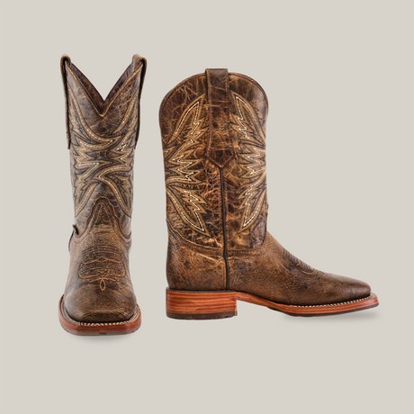 The Rustic Camel Brown Cowboy Boots, made from premium cowhide leather, feature intricate white stitching, wooden heels, and a slip-resistant sole. The design includes a square toe with the left boot shown from the side and the right facing forward.