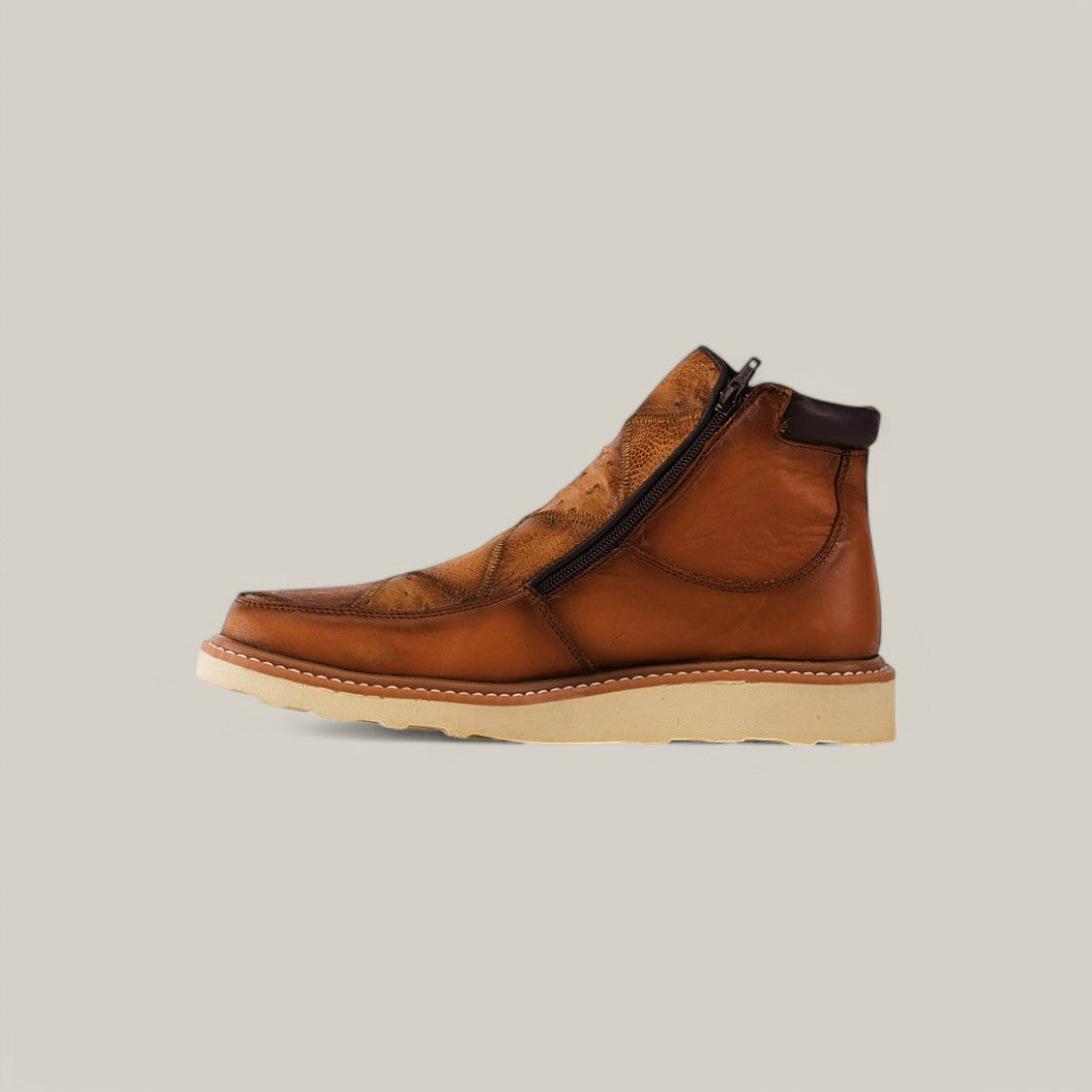 The Exotic Ostrich - Fawn ankle boot features a side zipper, light beige sole, visible stitching, and a textured pattern in rich ostrich leather against a neutral backdrop.