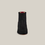 A front view of the Prime Suede Black Round Toe boot features a single black suede ankle design with a flat brown sole and round toe against a plain white background. Its absence of visible laces or zipper creates a sleek and minimalist style.