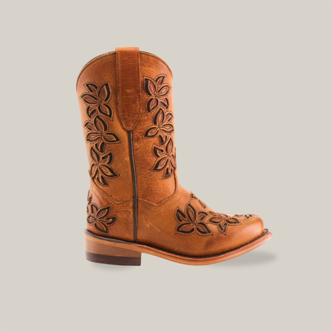 The Cosala Honey - Snip Toe is a brown cowboy boot crafted from genuine leather, featuring floral patterns on the shaft and toe. It has a low wooden heel, rounded snip toe, and intricate stitching details for the classic western look.