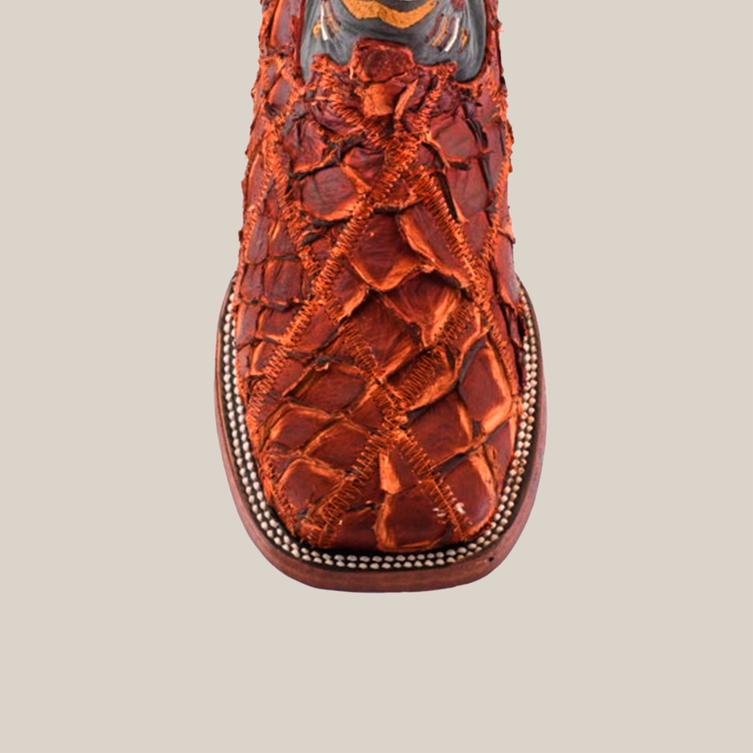 A close-up of the Exotic Pirarucu Fish Patchwork Cogñac Square Toe boot showcases intricate textured patterns reminiscent of exotic fish skin and decorative stitching at the top, isolated beautifully on a white background.