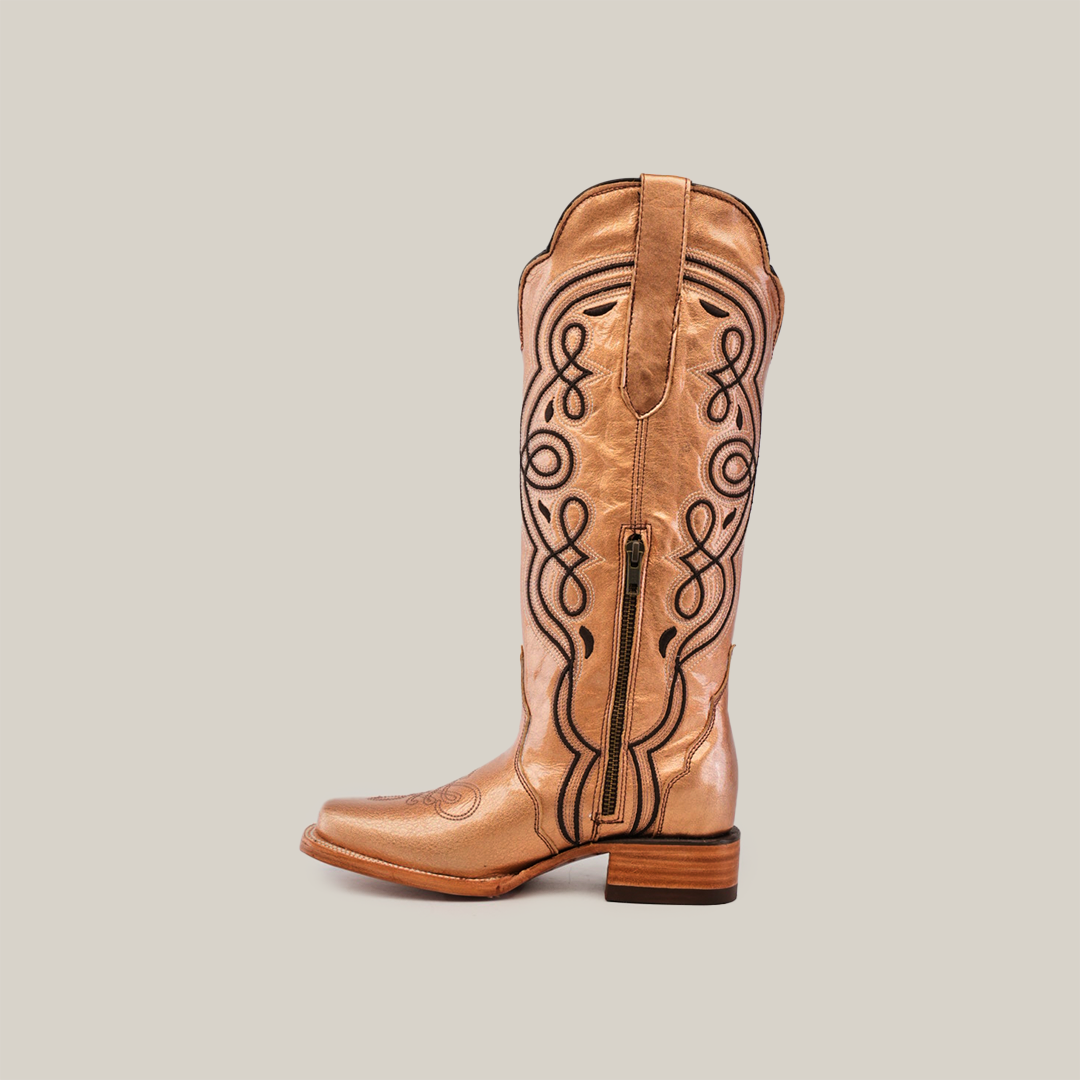 A single Eden Rose Gold boot, with tan leather and intricate black embroidery, stands elegantly against a light gray background. It features a narrow square toe, side zipper, and wooden heel, adding an elegant touch to its design.