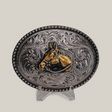 The Stud Horse Buckle is an ornate, oval-shaped Texas-style creation in alpaca silver, featuring intricate western scrollwork with a central gold horse head design against a neutral background.