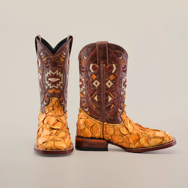 The Exotic Pirarucu Fish Patchwork Honey Square Toe boots feature textured, patterned leather with a brown and tan patchwork design, geometric designs on the shafts in white, yellow, and brown, and a uniquely rough texture inspired by pirarucu fish on the feet.