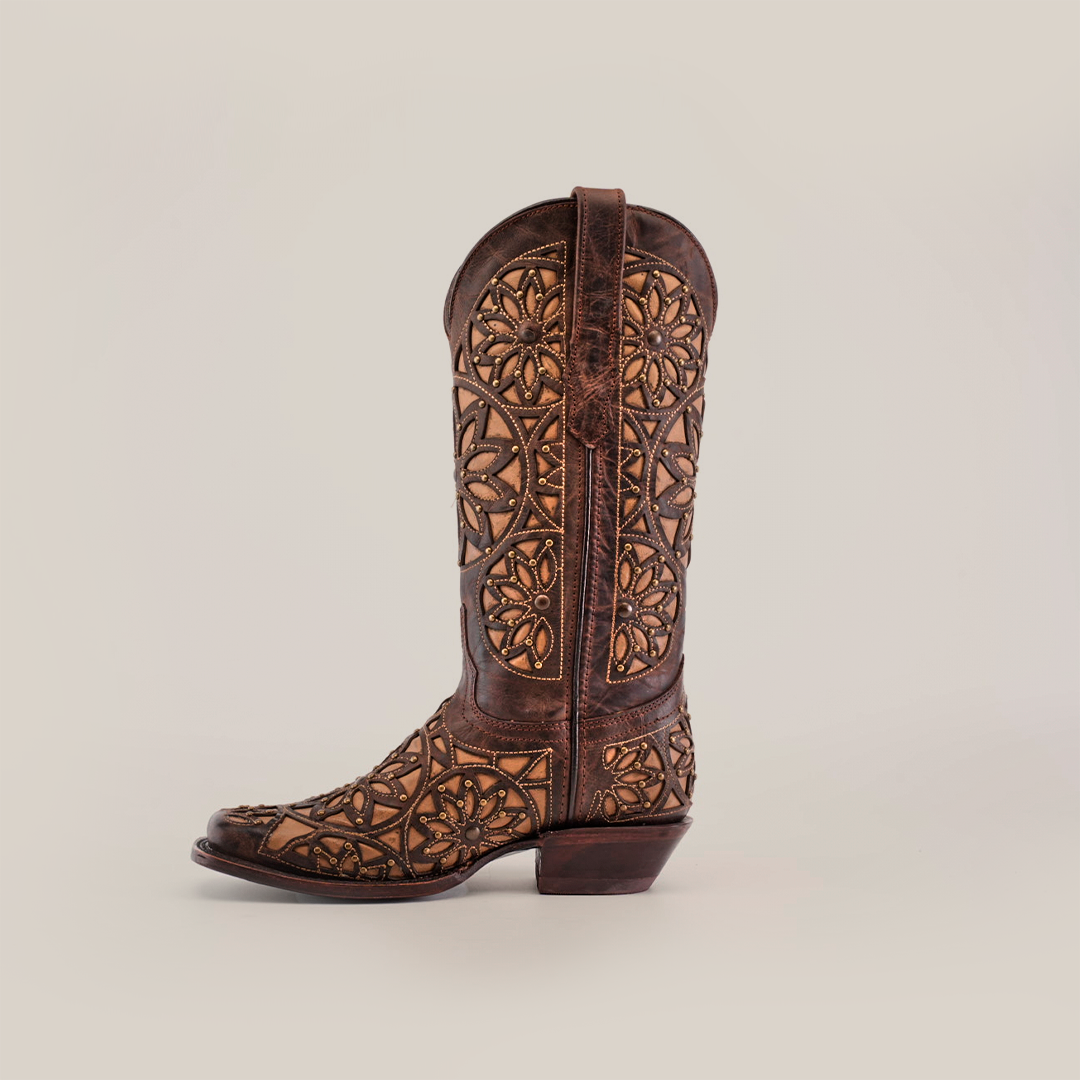 A single Vitralli Studs Tabaco boot, featuring premium leather with ornate brown and tan patterns, stands upright against a plain white background. Detailed stitching and decorative cutouts highlight its handcrafted artistry.