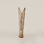 The Brittany Gold - Tall Shaft - Snip Toe cowboy boot, handcrafted for women, is shown alone on a simple gray backdrop. It features intricate stitching and a pointed toe with a subtly raised heel, standing upright and facing forward.