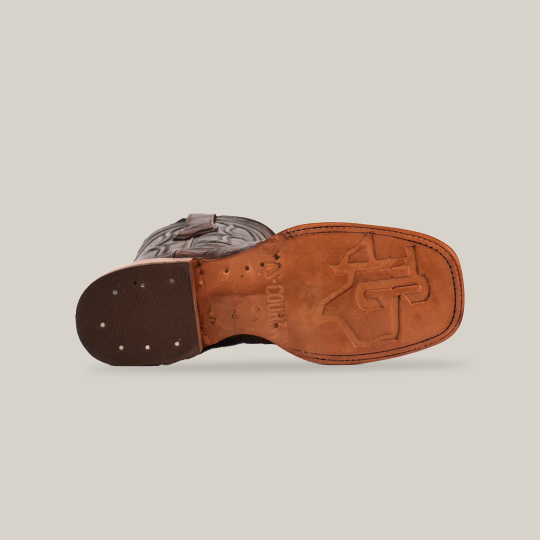 The Gator Print Rustic Brown - Square Toe cowboy boot is shown on its side, revealing a stamped sole design with metal studs. The boot features a decorative stitched pattern on the upper and a classic square toe, all visible from the side.