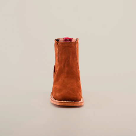 Against a white backdrop, the Prime Suede Brick boot stands out with its brown suede finish and distinctive red plaid lining at the top. Its unique square toe design offers a contemporary flair while maintaining a classic silhouette.